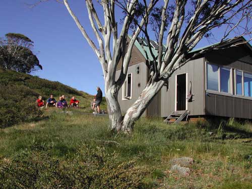 Illawong Lodge in summer with a group of bushwalkers sitting on the grass
